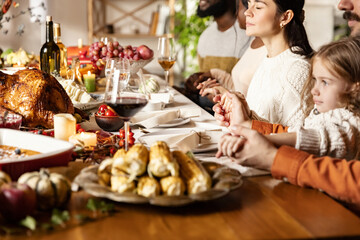 Happy family celebrate Thanksgiving day, sitting at table with roasted turkey and holiday traditional food, dishes.