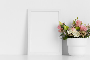 White frame mockup with a bouquet of roses on the white table.