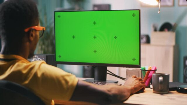Black man using computer with chromakey screen