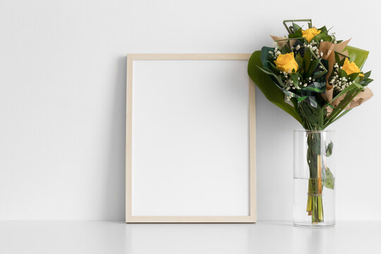 Wooden frame mockup with a bouquet of roses on the white table.