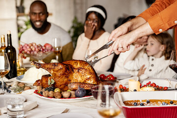 Close-up happy young men and women, married couple celebrate Thanksgiving day. Family dinner with roasted turkey