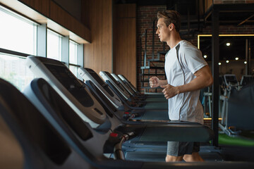 Fototapeta na wymiar side view of sportsman running on treadmill in gym.