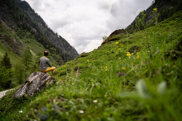 Fototapeta premium Junger Mann wandert auf Wanderweg in den Bergen von Salzburg bei bewölktem Wetter
