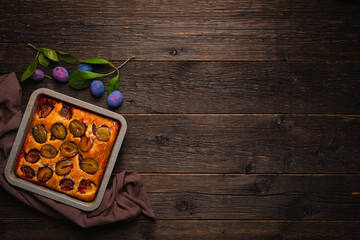 Plum cake in baking dish top view with copy space