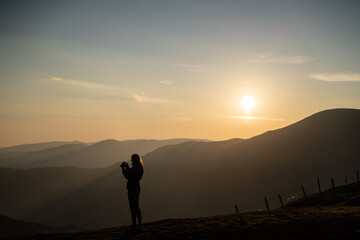 Junge Frau fotografiert nach Wanderung bei Sonnenaufgang am Berg in Salzburg Österreich