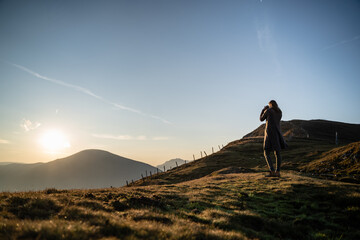 Junge Frau fotografiert nach Wanderung bei Sonnenaufgang am Berg in Salzburg Österreich