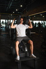 Fototapeta na wymiar full length view of sportsman training on arm extension exercising machine in gym.