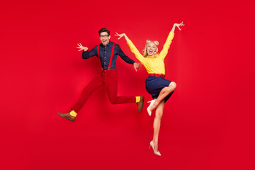 Full length body size view of trendy cheerful crazy couple jumping dancing boogie twist isolated over bright red color background