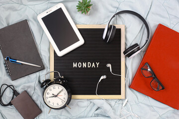 Monday flat lay concept with multimedia accessories, book and pen, flowers, alarm clock, red book and glasses on white background