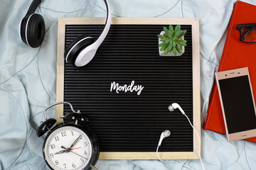 Monday flat lay concept with decoration of headphones, flowers, a piece of glasses and books, smart phone, earphones and alarm clock on white background
