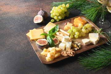 Christmas cheese platter with different cheese and grapes, nuts, olive, figs on a brown background...