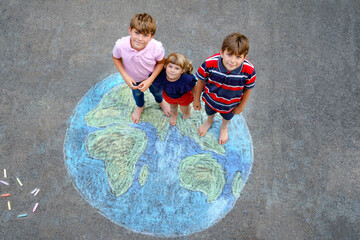 Little preschool girl and two school kids boys with earth globe painting with colorful chalks on...