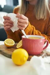 Vertical image of ill woman with tissue and hot tea