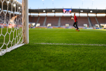 Obraz premium Net and the post in the football goal at the stadium and goalkeeper in the background.
