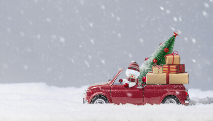 Snowman in Red car delivering christmas tree and presents at snowy background.