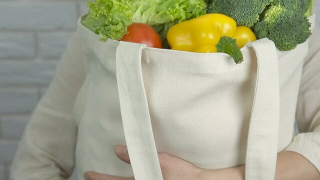 Woman with vegan bag. A woman show her big shopper with vegetables after shopping.