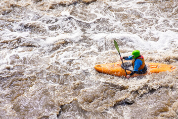 Fototapeta na wymiar a rower on a kayak goes along a mountain river. dangerous active rest on the river