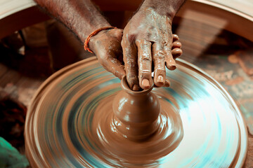 A slow shutter speed shot of a potter hand making a pot from a pottery wheel at Hubli, Karnataka, India.