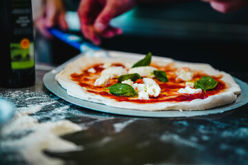 pizza chef preparing raw dough pizza olive oil basil mozarella fresh italian style napoletana napoli pizza about to be in oven