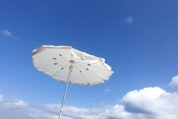Weißer stylischer Sonnenschirm vor blauem Himmel