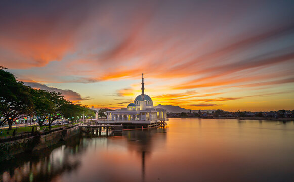 the view of a mosque during the azan solat magrib on the banks of the sarawak river which is the color of the red sunset