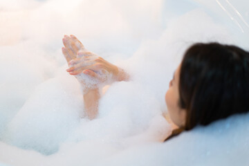 Close up relaxed woman touching the skin enjoying bathing with foam in bathtub.