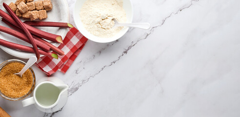 Ball of dough and ingredients flour, water, butter, sugar and rhubarb for baking on white marble background with dusting of flour. Recipe step by step. Selective focus. Top view. Banner.