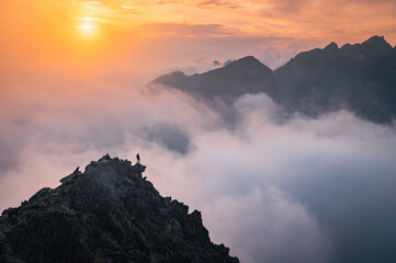 Hiker with open arms at the top of the hill. Beautiful sunset light and mist in background. Mountains scenery. Edit space.