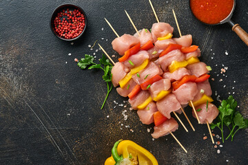 Raw shish kebab on wooden board, spices, herbs and vegetables on dark grey background. Barbecue Raw...
