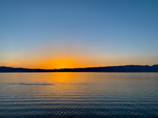 Idyllic orange sunset at the lake, silhouette of the mountains background