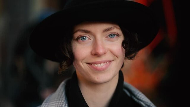 Portrait of young beautiful caucasian woman in black hat looking at the camera at the sunset. Close up of happy young girl smiling. High quality 4k footage