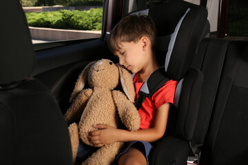 Little boy fastened with car safety belt in child seat sleeping