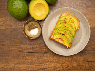The toast then topped pepper with sliced avocado, salt, and cayenne pepper. Avocados are a versatile fruit to slice, mash, or fill. Top view. Space for text. Health fruit concept