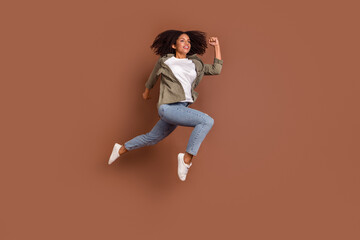 Fototapeta na wymiar Full length profile photo of cool young brunette lady run wear shirt jeans shoes isolated on brown background