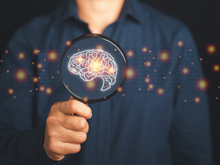 Close-up of a businessman hand holding magnifying glass looking at a digital image of the brain. Artificial Intelligence. AI Technology. Concept of human intelligence with a human brain and thinking