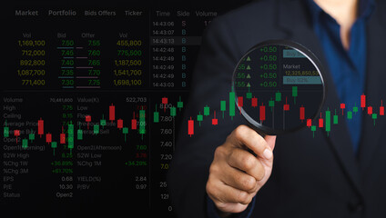 Close-up of a businessman hand holding magnifying glass looking at analyzing data stock market. Close-up photo. Business and financial investment concept