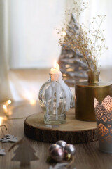 Wooden Christmas ornaments, lit candles and vase with gypsophila flowers. Hygge at home. Selective focus.