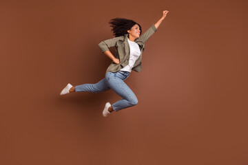 Full size profile photo of dreamy cheerful girl raise fist look empty space isolated on brown color...