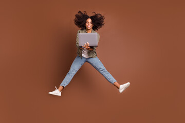 Fototapeta na wymiar Full size portrait of carefree energetic active lady hold netbook have good mood isolated on brown color background