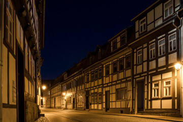 Nachtaufnahme einer beleuchteten Straße mit Fachwerkhäusern in der Altstadt von Stolberg im Harz.