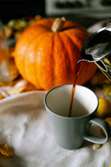 There is a layout of pumpkin and autumn leaves on the kitchen table 