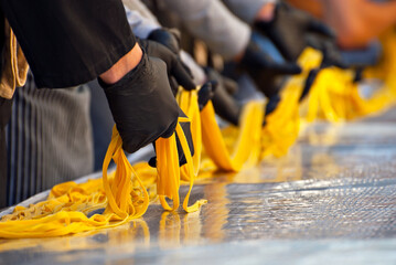 Demonstration of spaghetti production at the fair. Setting a record for the longest pasta in the world. Yellow long pasta stretched on the table.