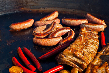Sausages are fried on an electric grill. Different types of sausages close up.