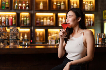 Nightlife concept in the night club a pretty woman with a pink drink in her hand looking very happy perhaps due to the atmosphere