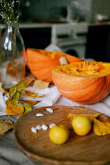 There is a layout of pumpkin and autumn leaves on the kitchen table 