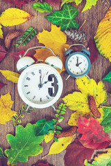 Fall Back Time - Daylight Savings End - Return To Winter Time. Autumn Leaves and Vintage Clock on a Wooden Background