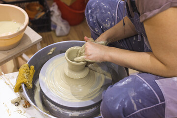 Female pottery artist shapes the clay on pottery wheel. Creative handmade craft. Closeup view