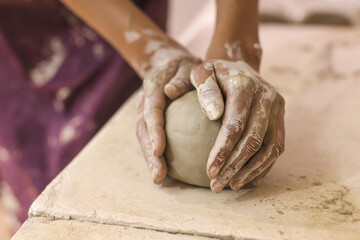 Female pottery artist hands shapes clay on table. Ceramic art studio.Close Up view . Creative...