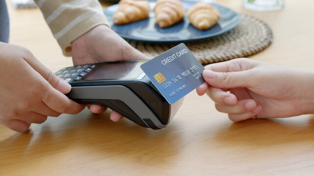 Close-up hand asia woman people work in small sme coffee cafe shop store owner use cashless wifi paywave nfc scan app smart pos reader sale in take out food drink order in urban city life contactless.