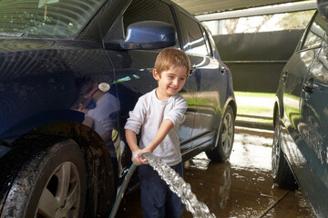 boy washing a car. kid washing a car at a car wash. Doing chores as kids can help develop character and responsibility. 